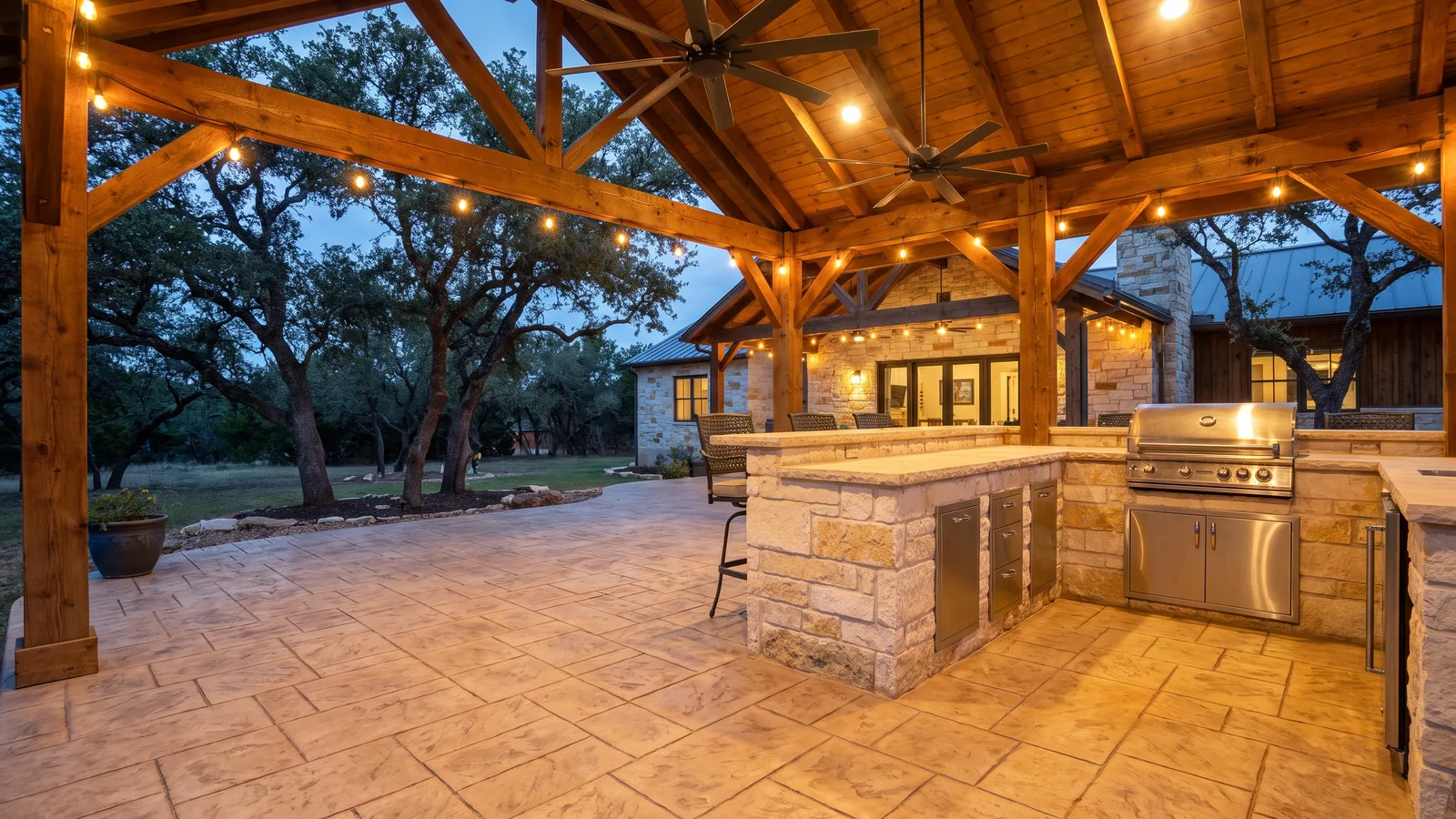 Stamped concrete patio and outdoor kitchen under a covered porch at a Texas limestone home